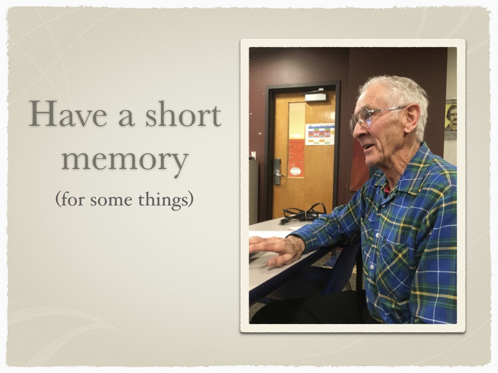 Older man in blue and green flannel shirt looking towards laptop. Caption is 