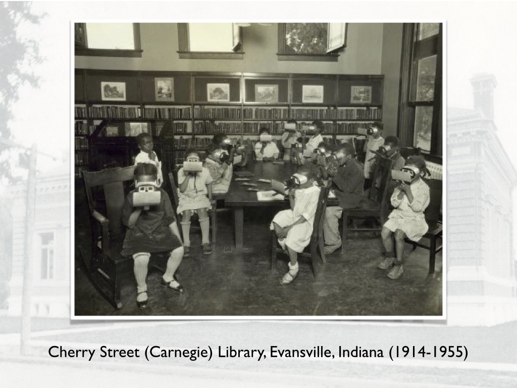 Old time image of a lot of young black children in a library looking at stereoscopic images. Caption says this is the Cherry Street Library in Evansville Indiana, open from 1914-1955