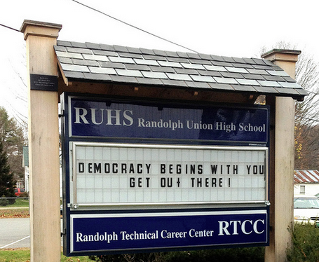  saying "democracy begins with you, get out there" in from of local high school