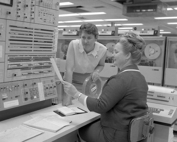 image of two women looking at soimething in front of on older mainframe. Black and white image