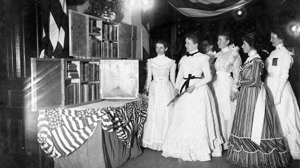 a bunch of women in victorian era dresses standing around some travelling libraries