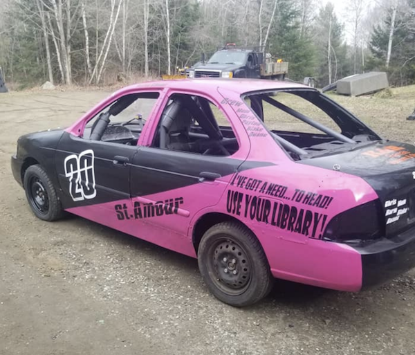 a black and pink stock car, number 20, with the caption "I've got a need... to read. USE YOUR LIBRARY" over the back tire